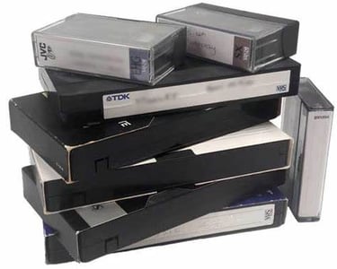 A stack of vintage VHS tapes and small video cassettes for analog media conversion.