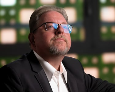 Robert in a suit and glasses holding a cell phone