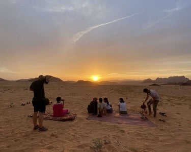 a group of people sitting on a blanket in the desert