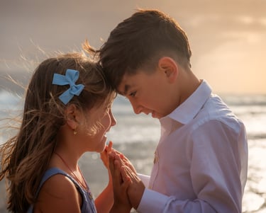a boy and girl standing in front of a body of water
