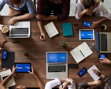a group of people sitting around a table with laptops