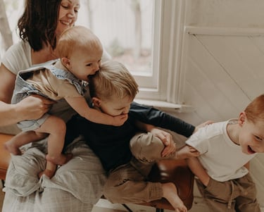 a woman holding a baby and two children