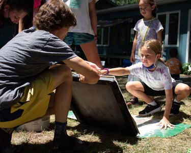 Teacher holding up a screen for papermaking in front of one of our youth students.