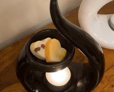 a black swirl ceramic wax burner with 2 heart shaped wax melts in the dish