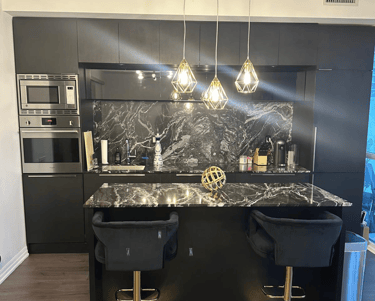 a kitchen with a marble counter top and black chairs
