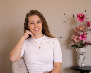 a woman, the writher, sitting in a chair with a flower in the background