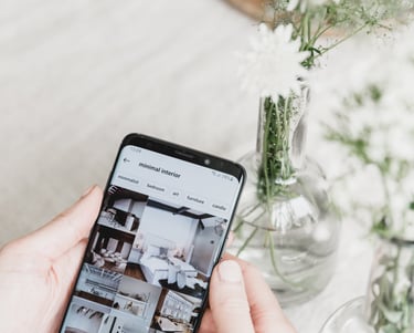 a person holding a phone with a camera and a vase with flowers