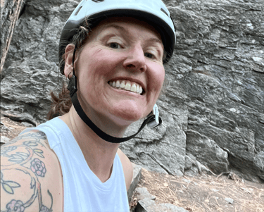 A smiling woman in front of a rock face