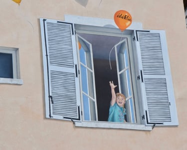 Détails d'une fenêtre en trompe-l'oeil peint sur une façade, un enfant avec ballons Ideklic, Jura 39