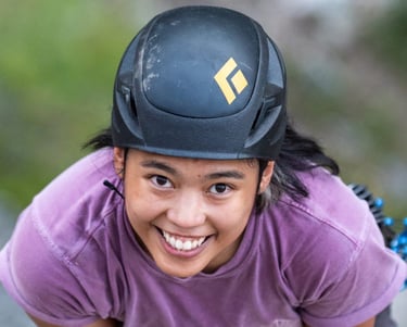 A smiling woman wearing a black helmet and purple shirt