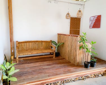 Rustic tropical bisita hostel reception bamboo furniture, wooden floors, and potted green plants.
