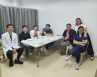 A group of Filipino doctors and medical professionals smiling while gathered around a table for a meeting.