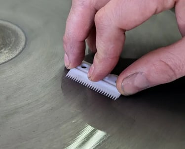 Clipper blade being hand-sharpened on diamond wheel