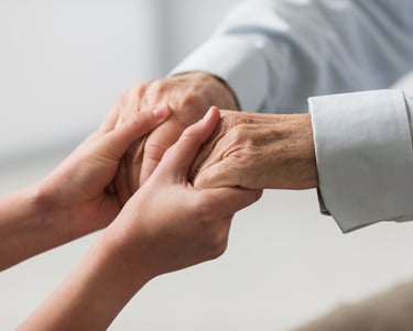 a woman caregiver holding a senior man's hand