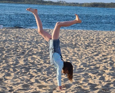 a happy person doing a handstand on a Sunshine Coast beach
