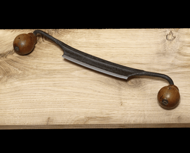An old style drawknife on a wooden table