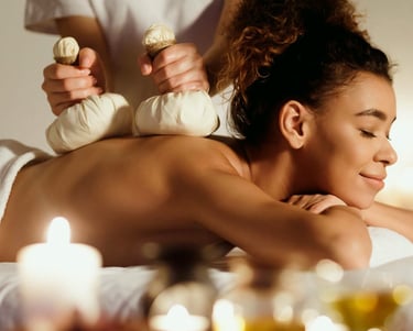 woman getting massage with bags of organic herbs