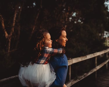 a young girl riding on a womans back on a wooden bridge