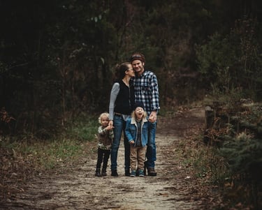 a family of four standing on a path in a wooded area