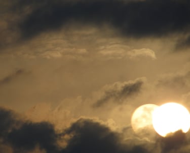 Doppelte Reflexion der goldenen Sonne, die bei Sonnenuntergang durch dunkle, dramatische Wolken leuc