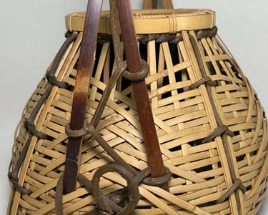 Handcrafted traditional woven bamboo basket with decorative rope knots and a sturdy handle.