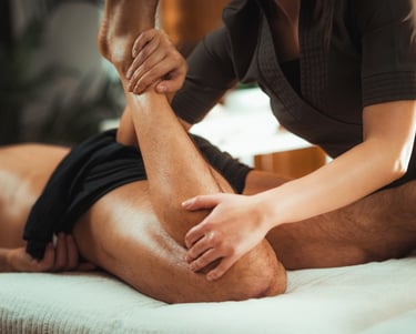 Massage therapist performing sports massage on male