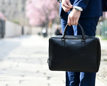 imagen de hombre de traje azul sosteniendo un maletín tapándose un reloj