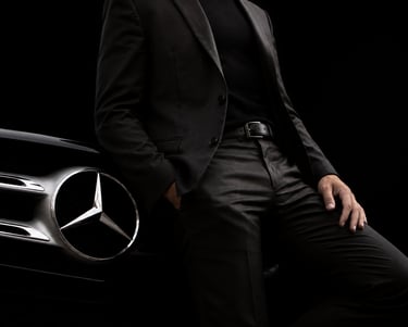 Homem em traje social ao lado de carro de luxo, representando sucesso e riqueza