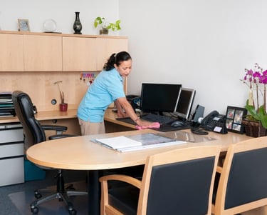 a woman cleaning a desk in an office setting