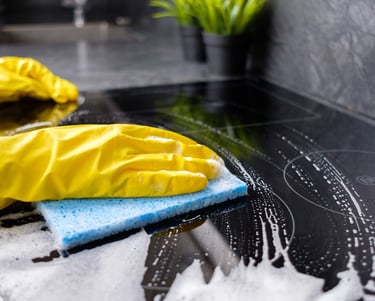 a person cleaning wearing yellow rubber gloves cleaning a stove top