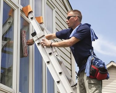 man on ladder washing windows in toronto