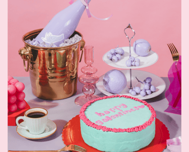 Galentines Day Party table decorated with a cake, a champagne bottle, coffee and goodies.