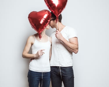 Couple kissing holding Valentine's Balloons