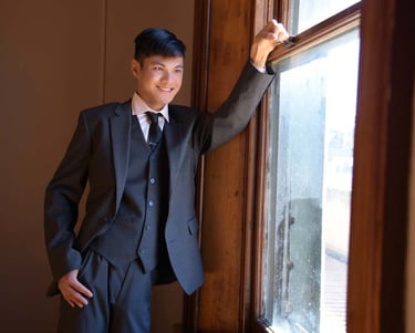 a man in a suit and tie standing in front of a window