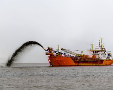 a boat with a large amount of dredging material coming out of the water