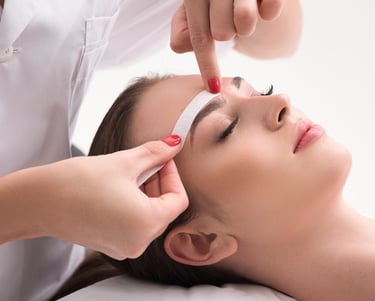 Una mujer está en el salón recibiendo un tratamiento de cera facial.