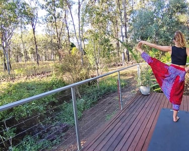 woman doing yoga on a deck with natural bush background