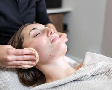 a woman getting a facial mask with a sponge at a salon
