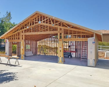 Large RV garage at framing stage with ladders and lift inside.
