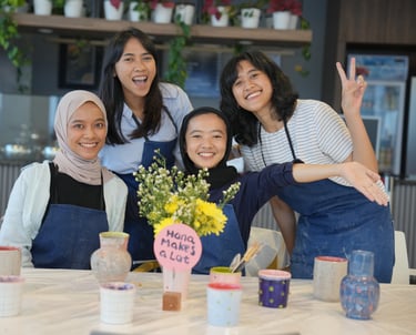 a group of women posing behind a table with flowers and handmade pots