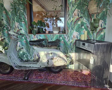Vintage-Vespa als dekoratives Highlight vor Dschungel-Tapete neben modernem Holz-Sideboard.