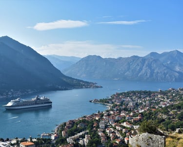 Cruise ship sailing to Port of Kotor Montenegro with houses and mountains in distance