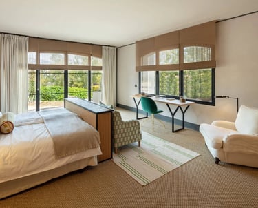 Bright bedroom suite at Villa La Gratitud with garden views, cozy seating, and soft natural tones.