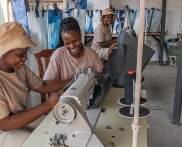 Young woman laughing whilst sewing bags