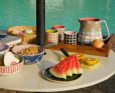 a table by the pool with a tray of food served on colorful tableware