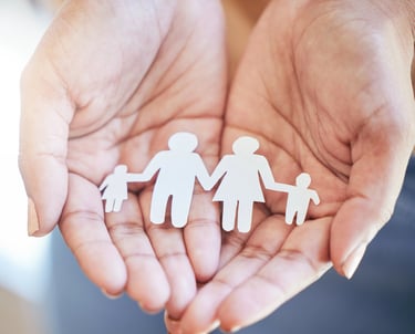 Manos sosteniendo figuras de papel de una familia, simbolizando Derecho de Familia.