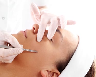 Vrouw met chirurgische handschoenen dat dode huidcellen weghaald met fijn mesje