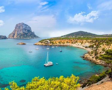 Sailboats in water with rock formation off the coast of Ibiza Spain