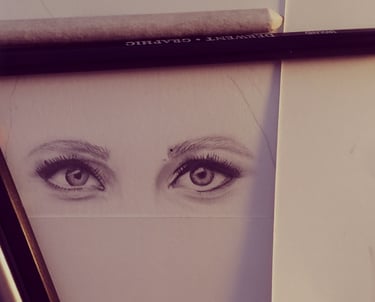 A drawing of human eyes with pencil and brush next to it