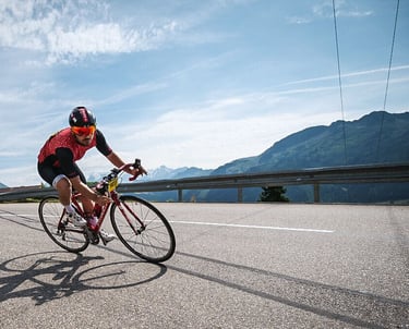 Un cycliste rouge se penche dans un virage dans un col des Alpes
